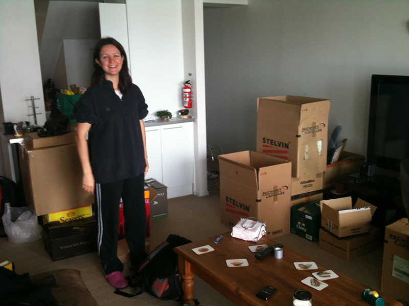 Fay standing in living room surrounded by boxes